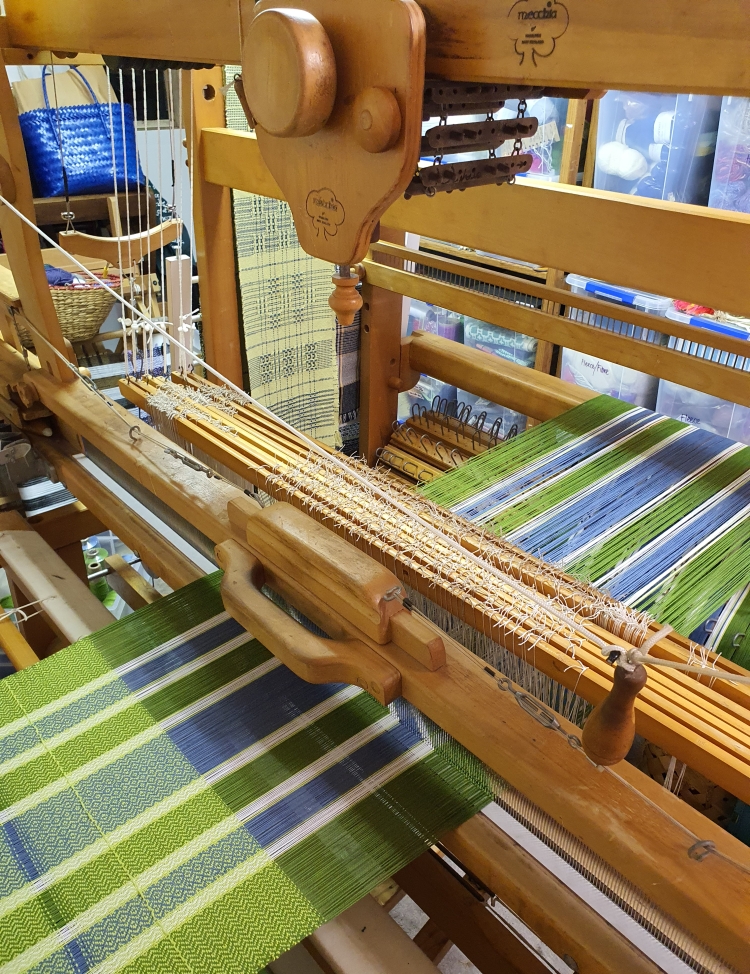 Green, blue and white cotton tea towels being woven on a Mecchia dobby loom.